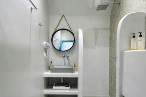 A bathroom with a sink, mirror, towel rack, and toiletries. - Hotel Armonia (Santorini)