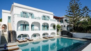 A white building with multiple balconies and a swimming pool. - Hotel Armonia (Santorini)