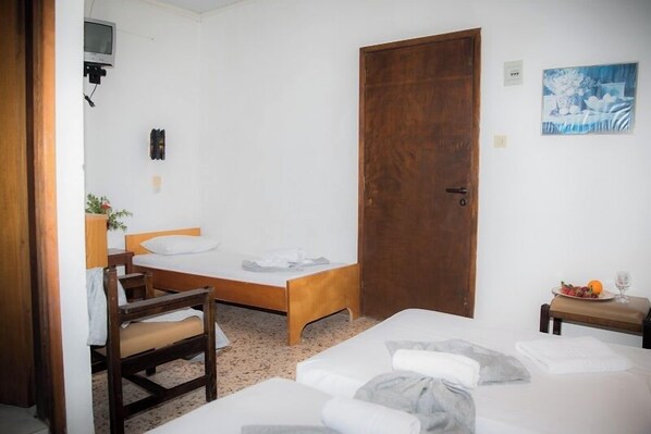 Una habitación pequeña y ordenada con una cama individual, una silla de madera, un escritorio con una planta y una puerta.