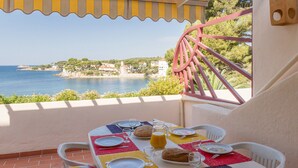 A table set for breakfast with a view of the sea and buildings in the background.