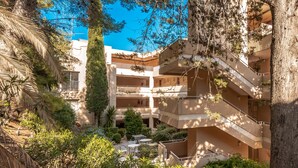A multi-story building with balconies, outdoor seating, and lush greenery.