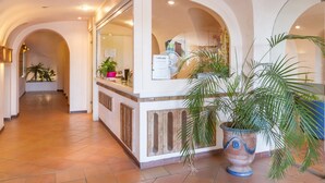 A reception area with a counter, potted plants, and a sign.