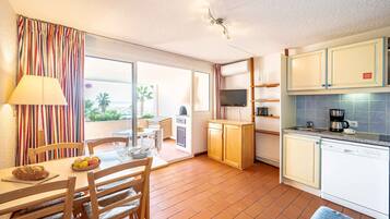 A compact kitchen with a dining area, a TV, and a view of the outdoors.