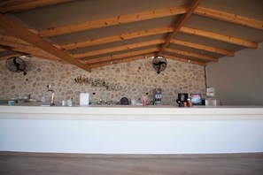 Eine Küche mit Steinwänden, Holzbalken, einer weißen Arbeitsplatte und zwei Deckenventilatoren.