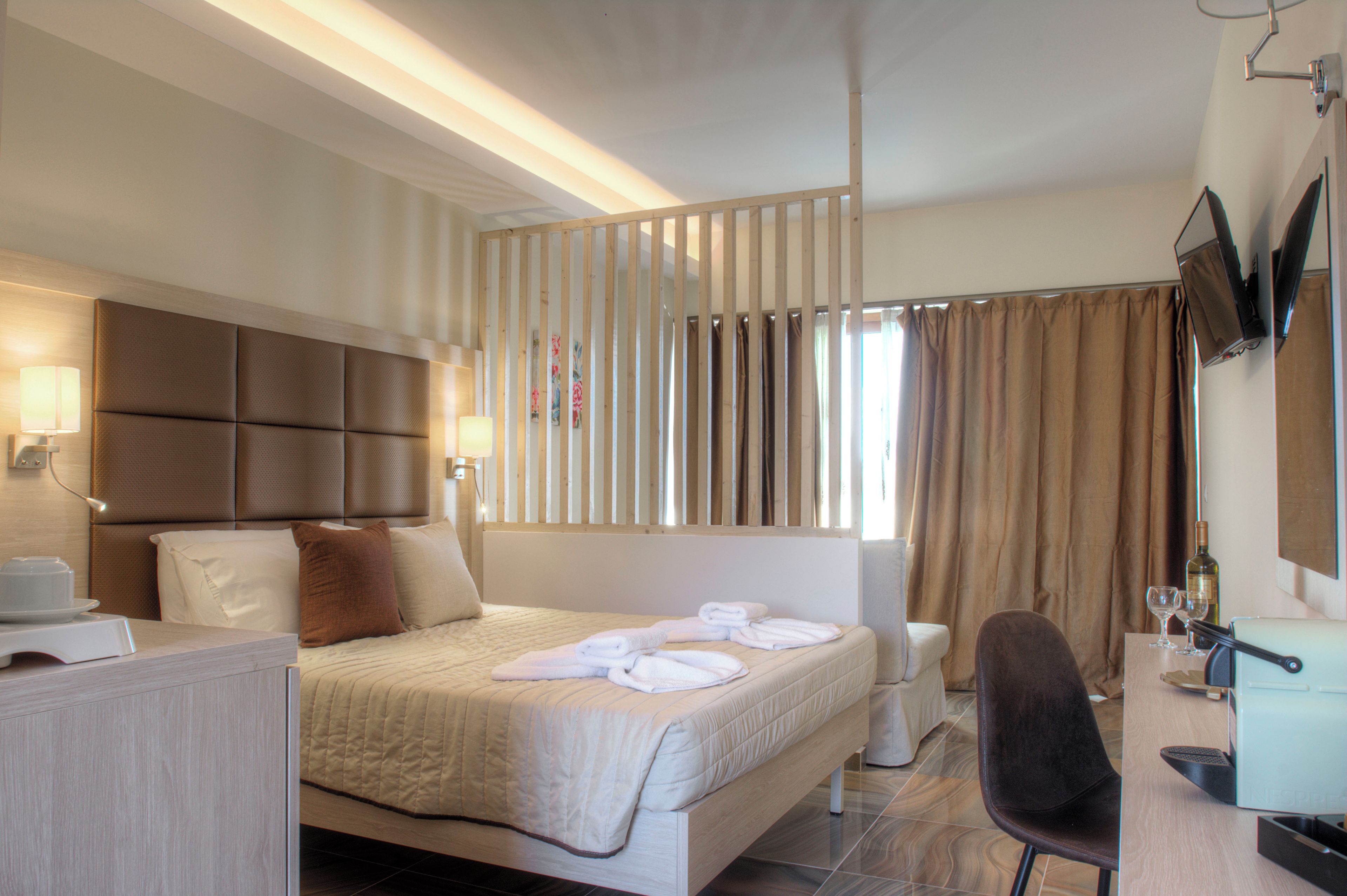 A hotel room with a bed, bedside table, lamp, chair, and a television mounted on the wall.