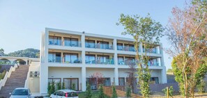 Ein mehrstöckiges Hotel mit Balkonen, ein Auto vor der Tür und eine Treppe zum Eingang.