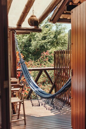 A wooden deck with a hammock, wooden chairs, and a wooden fence. - Villa Seychelles Cabanas (Imbituba)