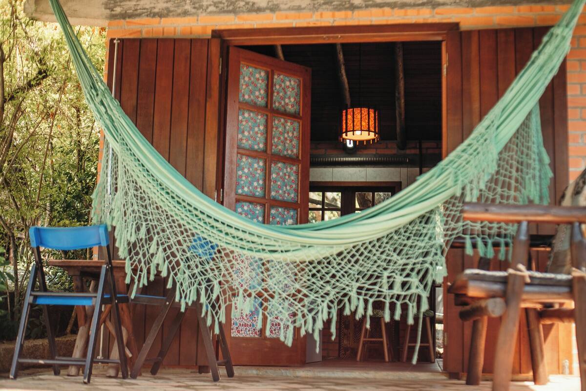 A hammock tied between wooden posts, a wooden door with glass panels, and a hanging light fixture.