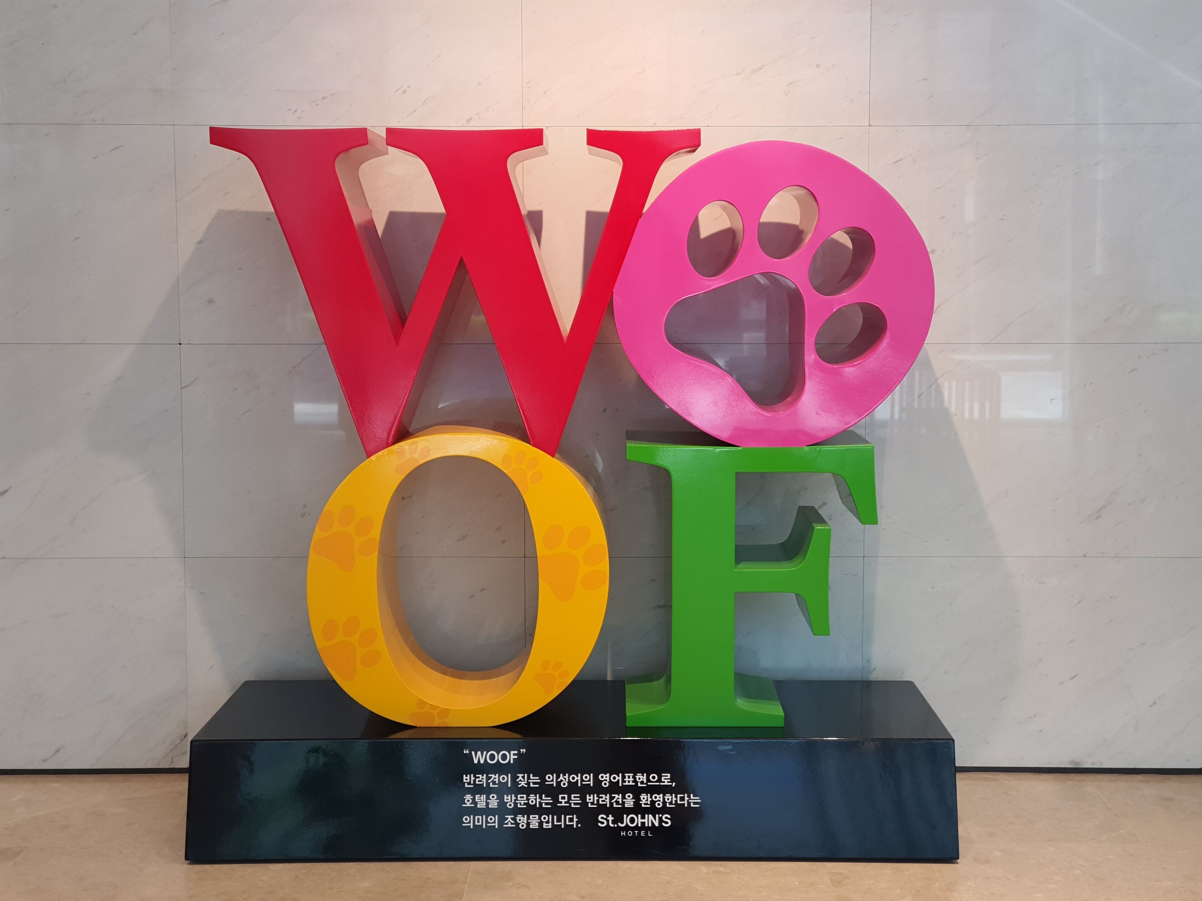Una exhibición de letras grandes y coloridas que deletrean "WOOF" con una huella de pata en la letra 'O'.