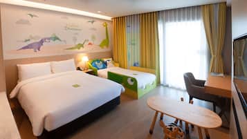 Habitación de hotel con dos camas, un escritorio y una silla. En la pared hay un mural que representa dinosaurios y nubes.