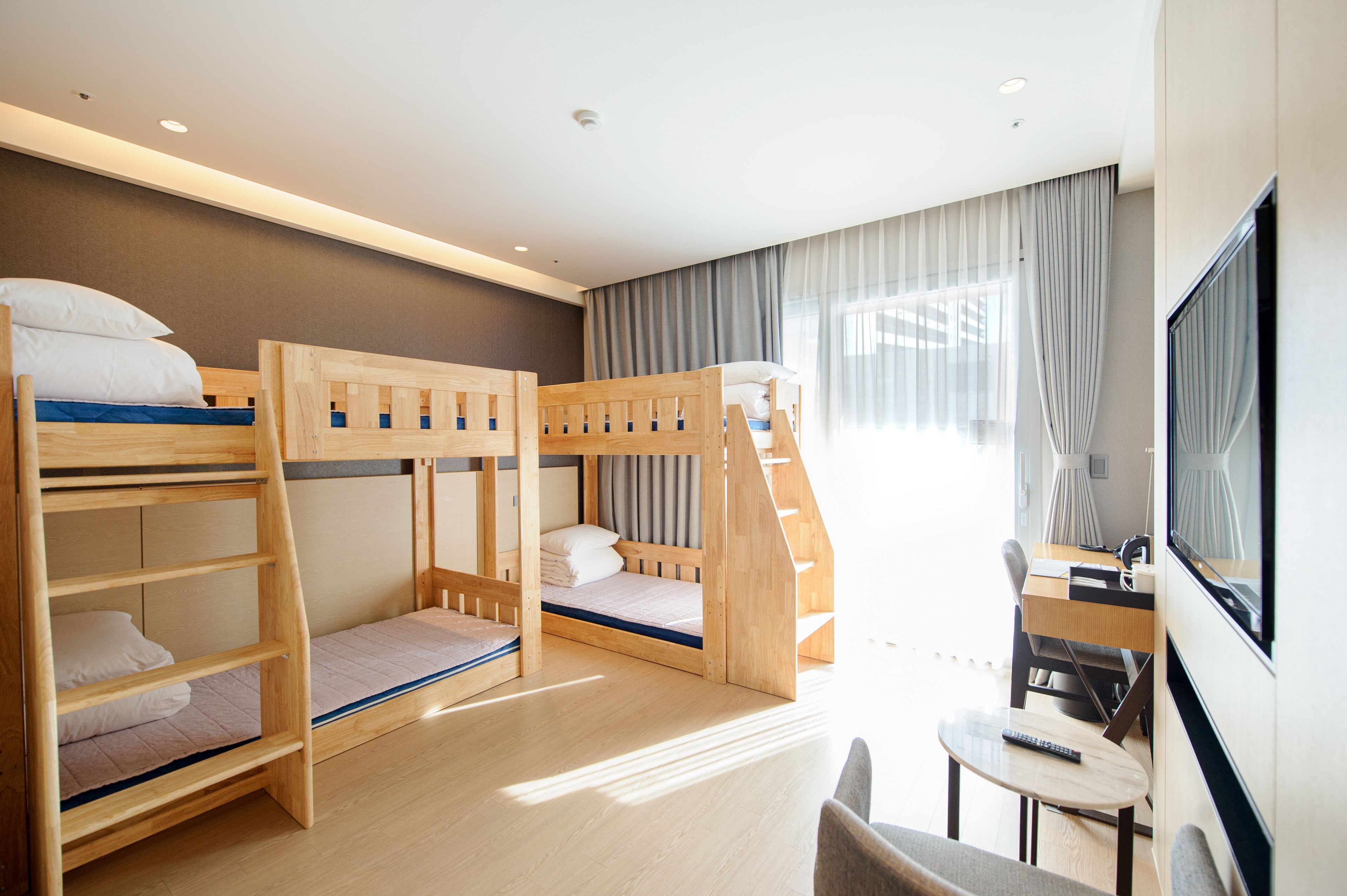 A hotel room with bunk beds, a desk, a chair, and a TV.