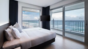 Een moderne hotelkamer met een groot bed, een flatscreentelevisie en een balkon met uitzicht op zee.
