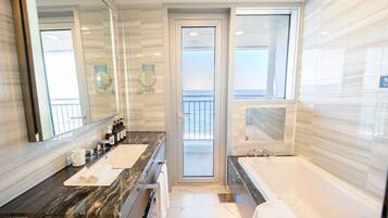 Une salle de bain moderne avec un grand miroir, deux lavabos, une baignoire et une vue sur le balcon.