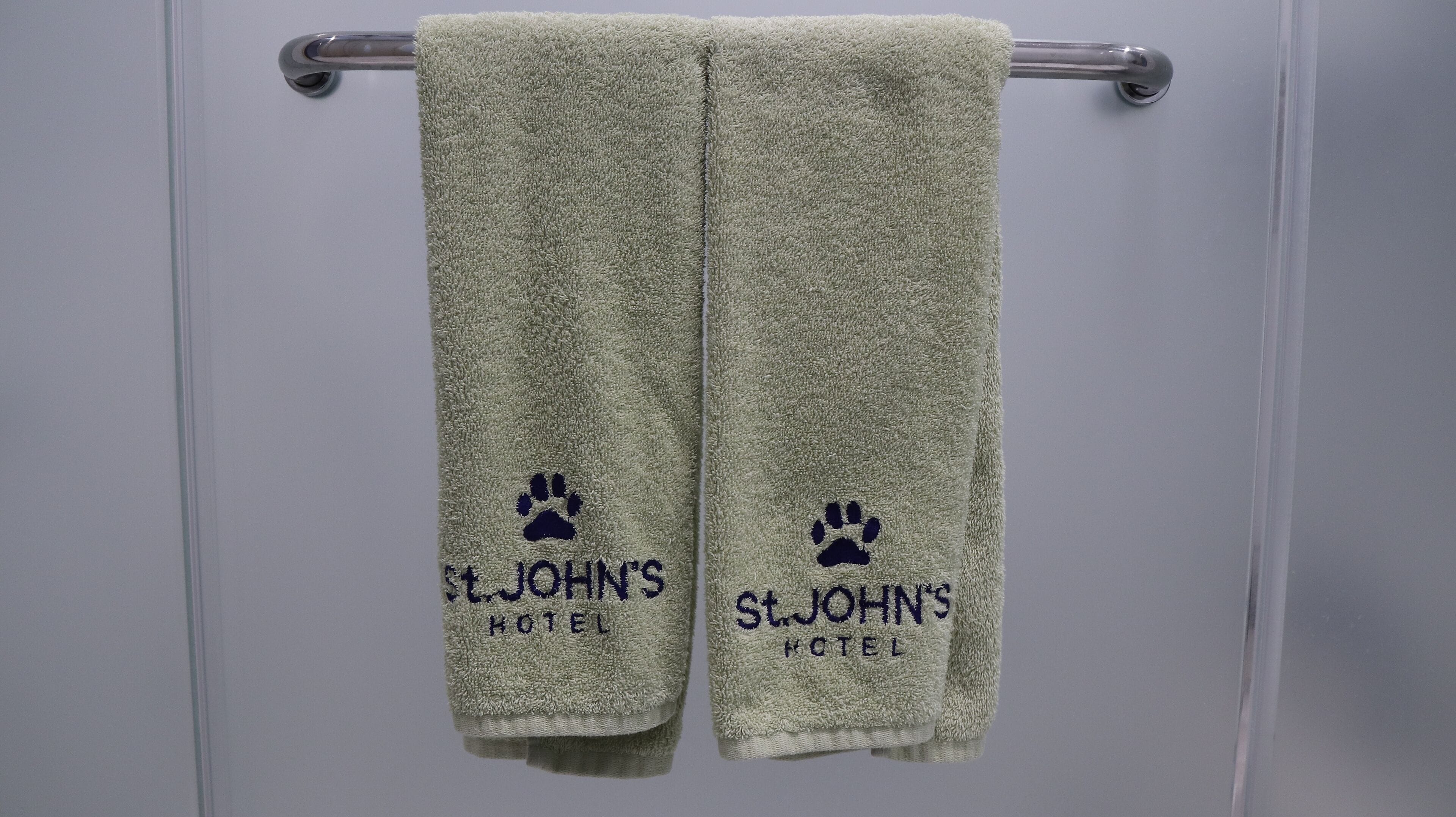 Two towels hanging on a metal towel rack with the text "St. John's Hotel" and a paw print logo.