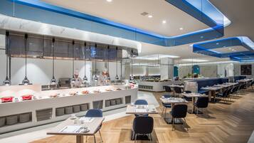A modern restaurant with a marble counter, blue ceiling accents, and neatly arranged tables and chairs.