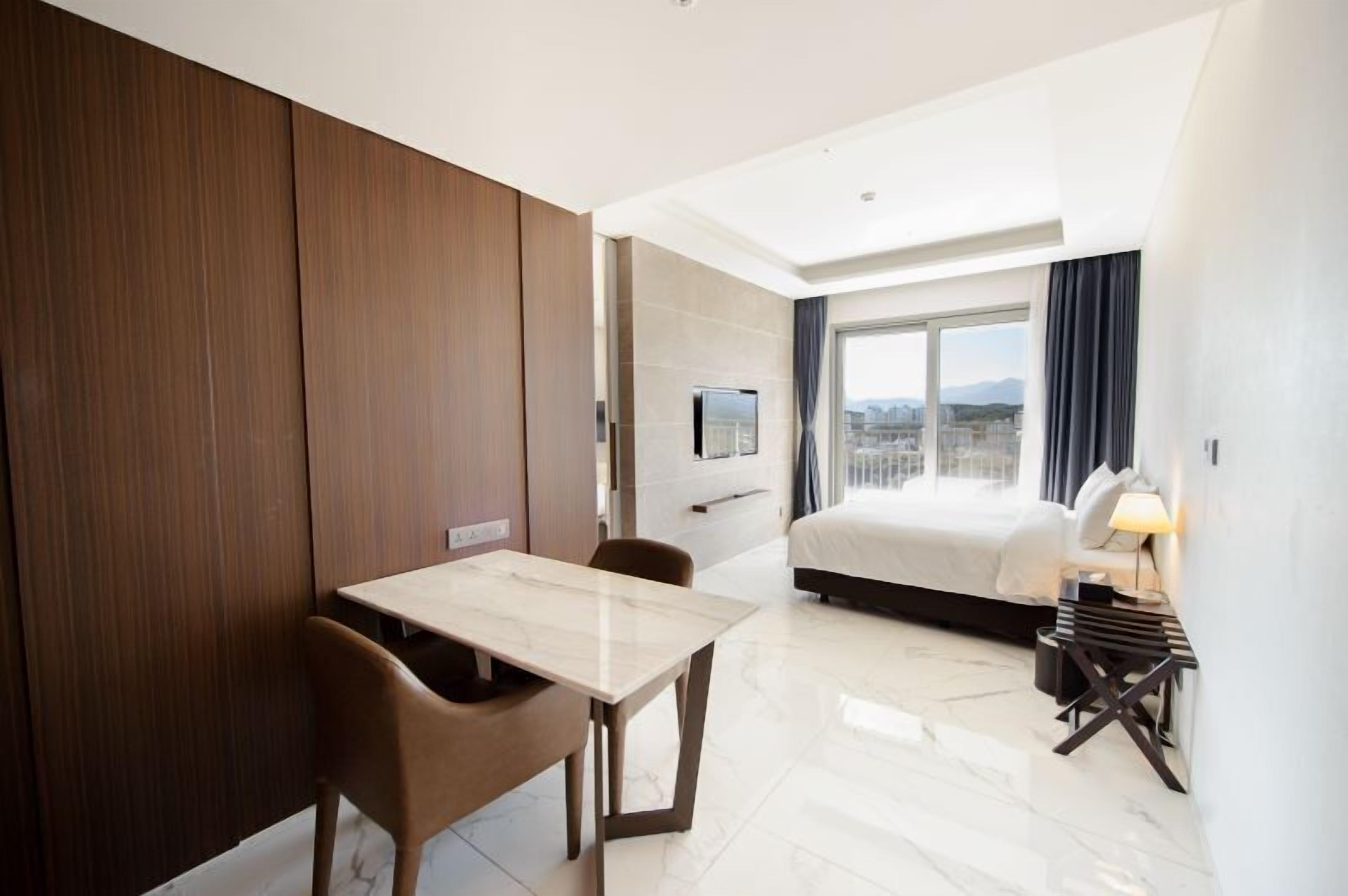 Una habitación de hotel moderna con cama, una mesa de comedor y televisión.