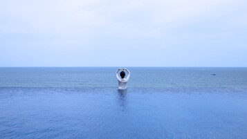 A person standing in calm sea water, making a heart shape with their hands.