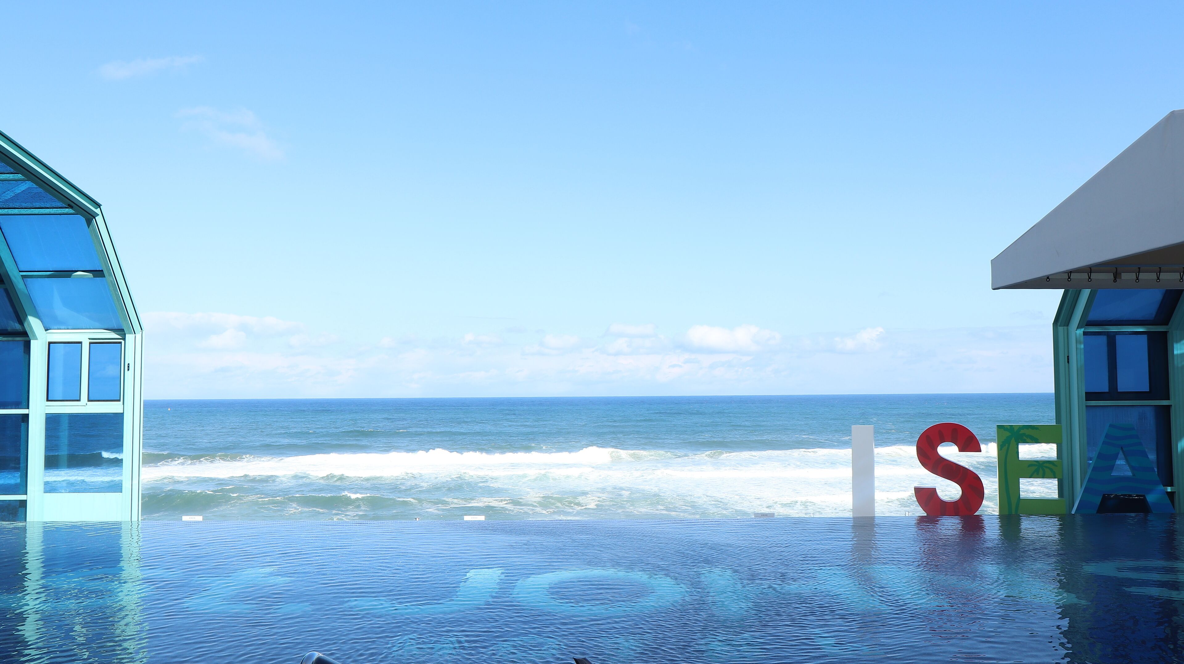 Une piscine à débordement offrant une vue sur l’océan et la plage.