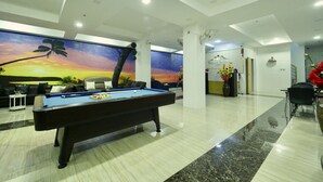 Una mesa de billar en el vestíbulo de un hotel con un mural al atardecer, una recepción y un área accesible para sillas de ruedas.