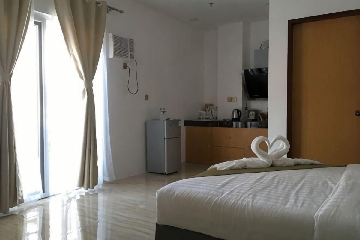 Une chambre d’hôtel équipée d’un lit, d’une petite kitchenette, d’un téléviseur et d’une porte coulissante.