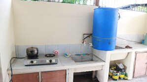 A kitchen with a gas stove, a blue water tank, and a sink. - Tabada Homestay (Mambajao)