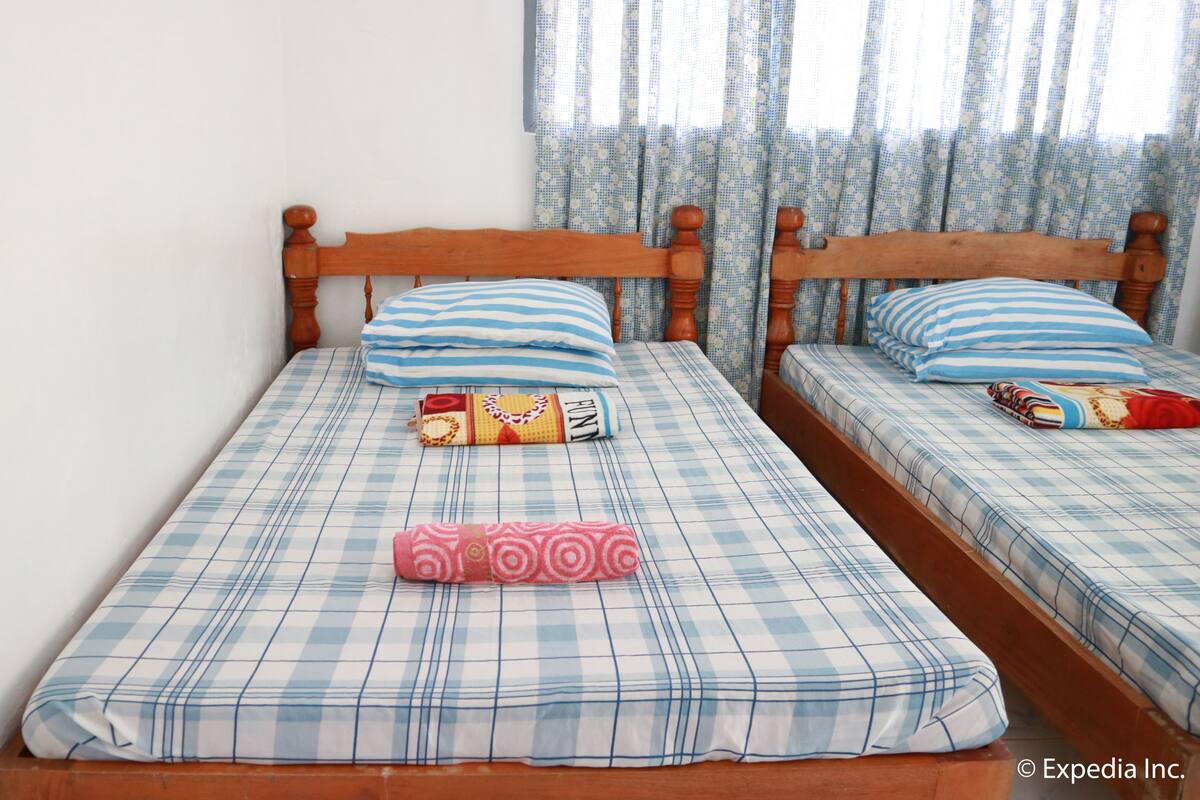 Una cama doble con una colcha escocesa, dos almohadas y un edredón enrollado.