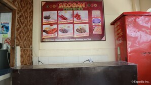 A food menu board with various dishes and prices, a no-smoking sign, and a Coca-Cola advertisement. - Tabada Homestay (Mambajao)