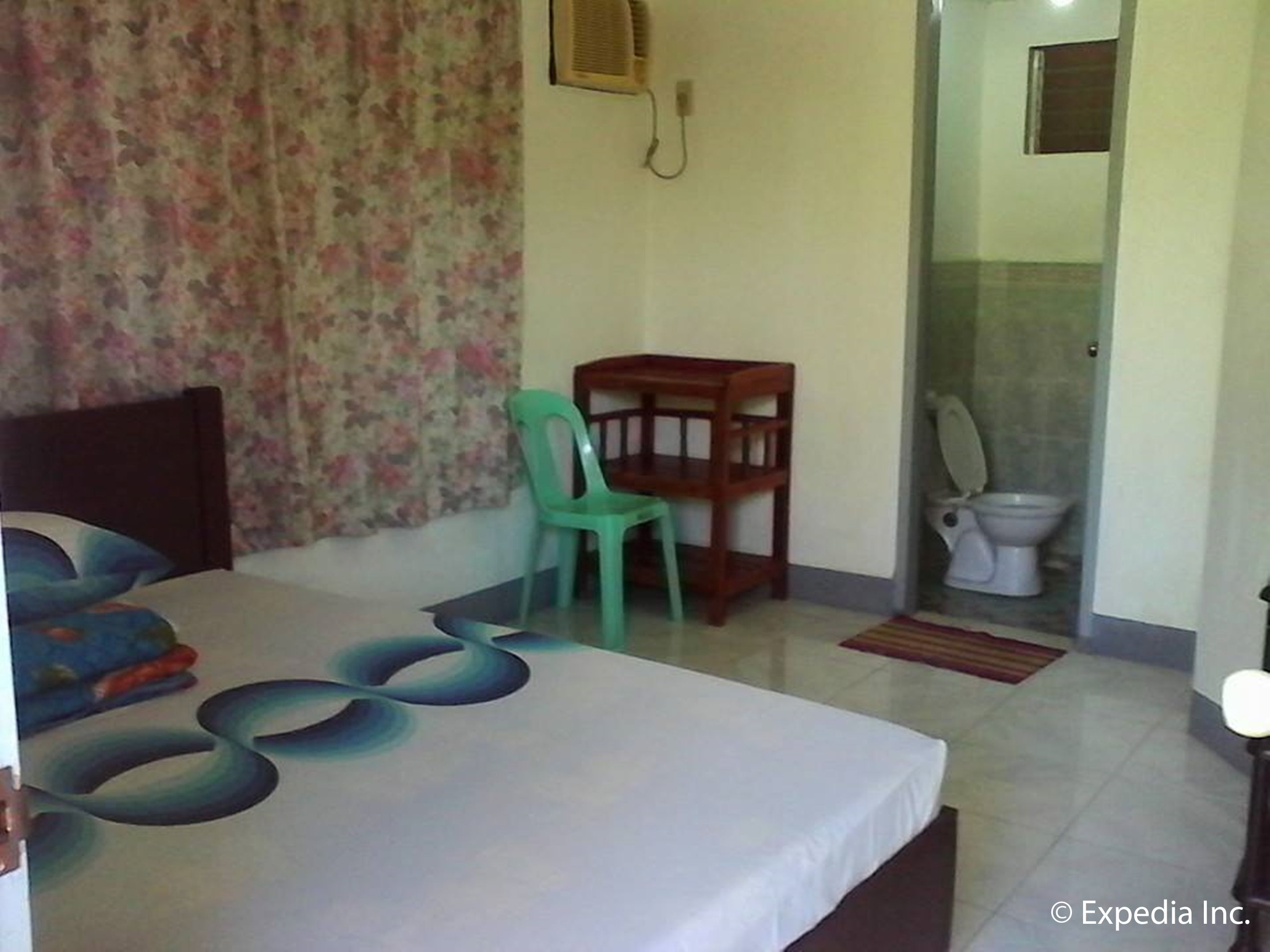 Un dormitorio con cama, una silla, un escritorio y un baño con inodoro y lavamanos.