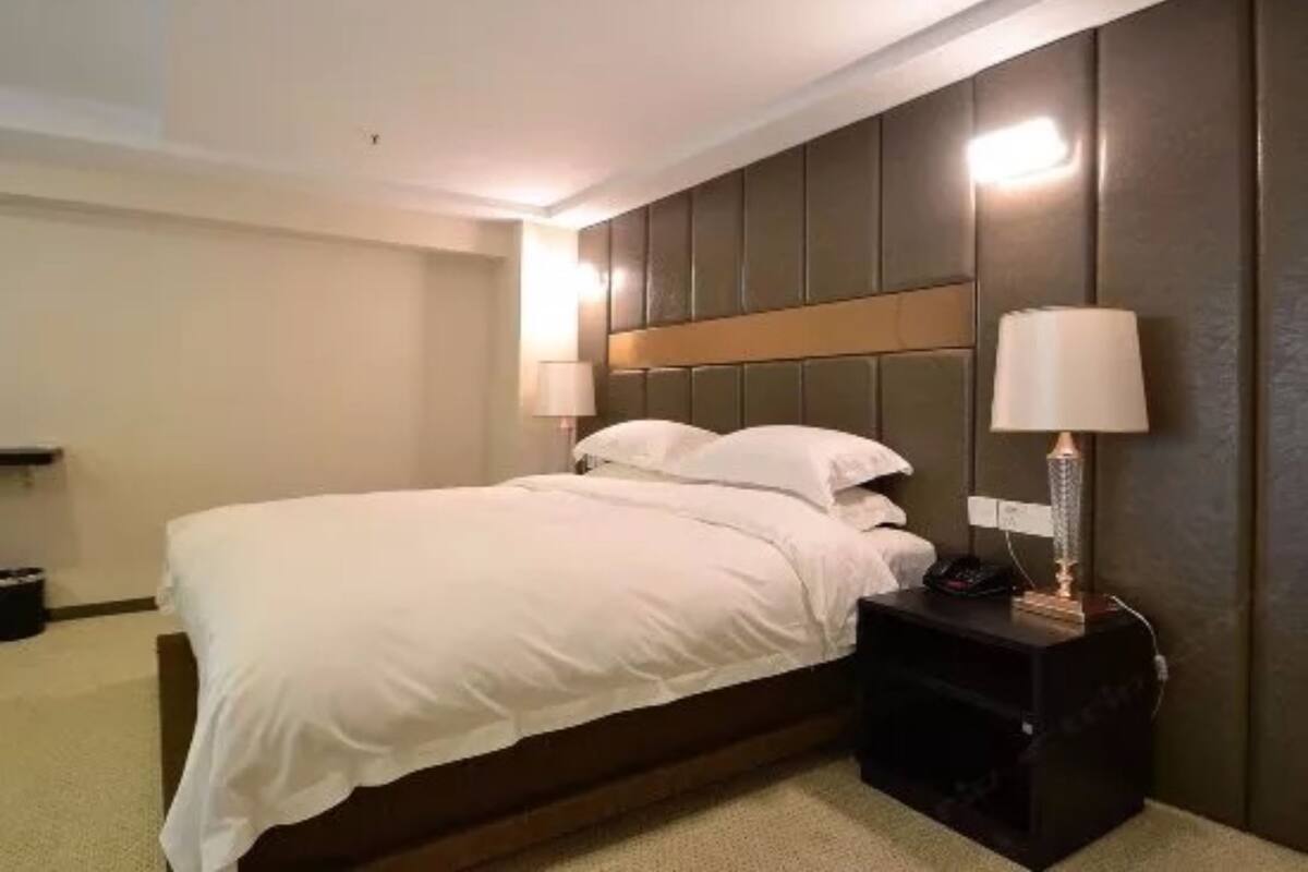 A hotel room with a bed, bedside lamps, and a nightstand.