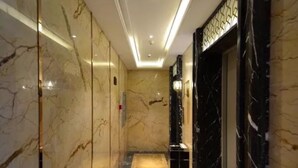 A marble-floored corridor with a modern elevator and a decorative wall panel. - Harbin Yuxuan Hotel (Harbin)
