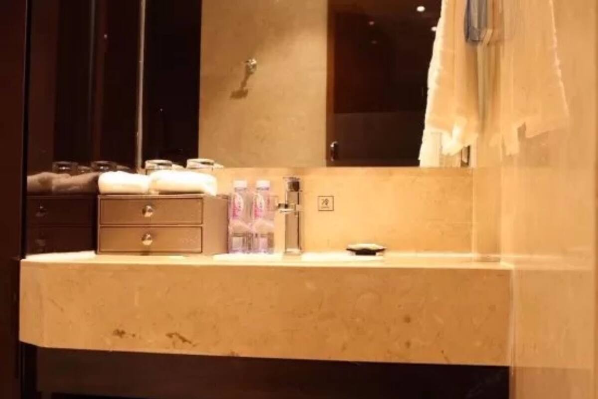 A bathroom with a marble sink, a mirror, a towel rack, and a shower curtain.