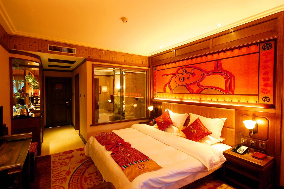 Quarto de hotel com uma cama grande, mesa de cabeceira e um espelho.