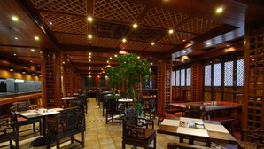 A traditional restaurant with wooden furniture, tiled floors, and decorative ceiling patterns. - Lijiang Golden Path Hospitality (Lijiang)
