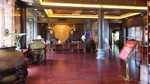 A traditional interior with wooden furniture, a reception desk, and a large decorative urn. - Lijiang Golden Path Hospitality (Lijiang)