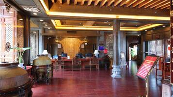 A traditional interior with wooden furniture, a reception desk, and a large decorative urn.