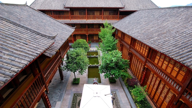 A traditional courtyard with wooden buildings, a central water feature, and a tiled roof. - Lijiang Golden Path Hospitality (Lijiang)