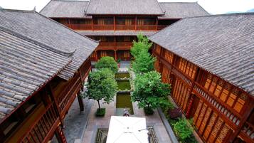A traditional courtyard with wooden buildings, a central water feature, and a tiled roof.
