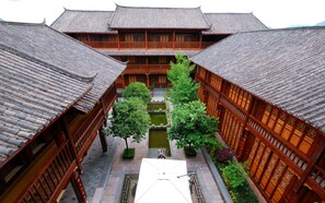 A traditional courtyard with wooden buildings, a central water feature, and a tiled roof. - Lijiang Golden Path Hospitality (Lijiang)