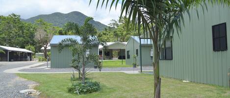 A green building with a covered outdoor area and a mountain in the background.