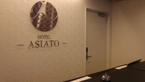 A hotel interior with a reception desk, a door, and a wall with a geometric pattern and the hotel's name. - Hotel ASIATO Namba (Osaka)