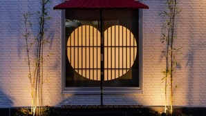 A building facade with a large window featuring a geometric pattern, flanked by vertical bamboo plants. - Hotel ASIATO Namba (Osaka)