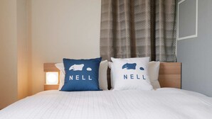 A bed with two pillows, each with a bear logo and the word 'NELL' on them. - Hotel ASIATO Namba (Osaka)