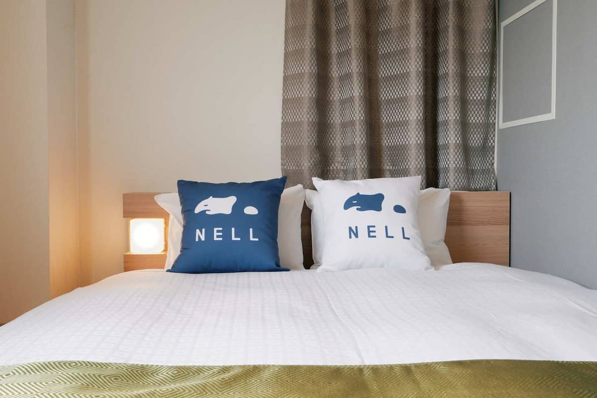 A bed with two pillows, each with a bear logo and the word 'NELL' on them.