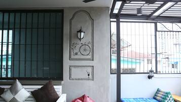 Ein Zimmer mit einem weißen Sofa, einem roten Sitzsack und einem blauen Sofa mit Kissen. Es gibt ein Fenster mit Metallgitter und einen Blick auf Gebäude im Freien.