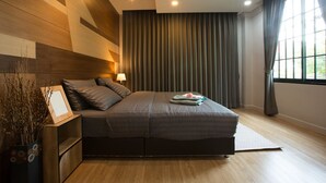 A modern bedroom with a large bed, a bedside table with a lamp, and a window with curtains. - PAMA House Boutique Hostel (Bangkok)