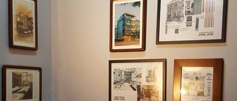 A room with a wall displaying framed architectural drawings and a small table with water bottles and a tissue box.