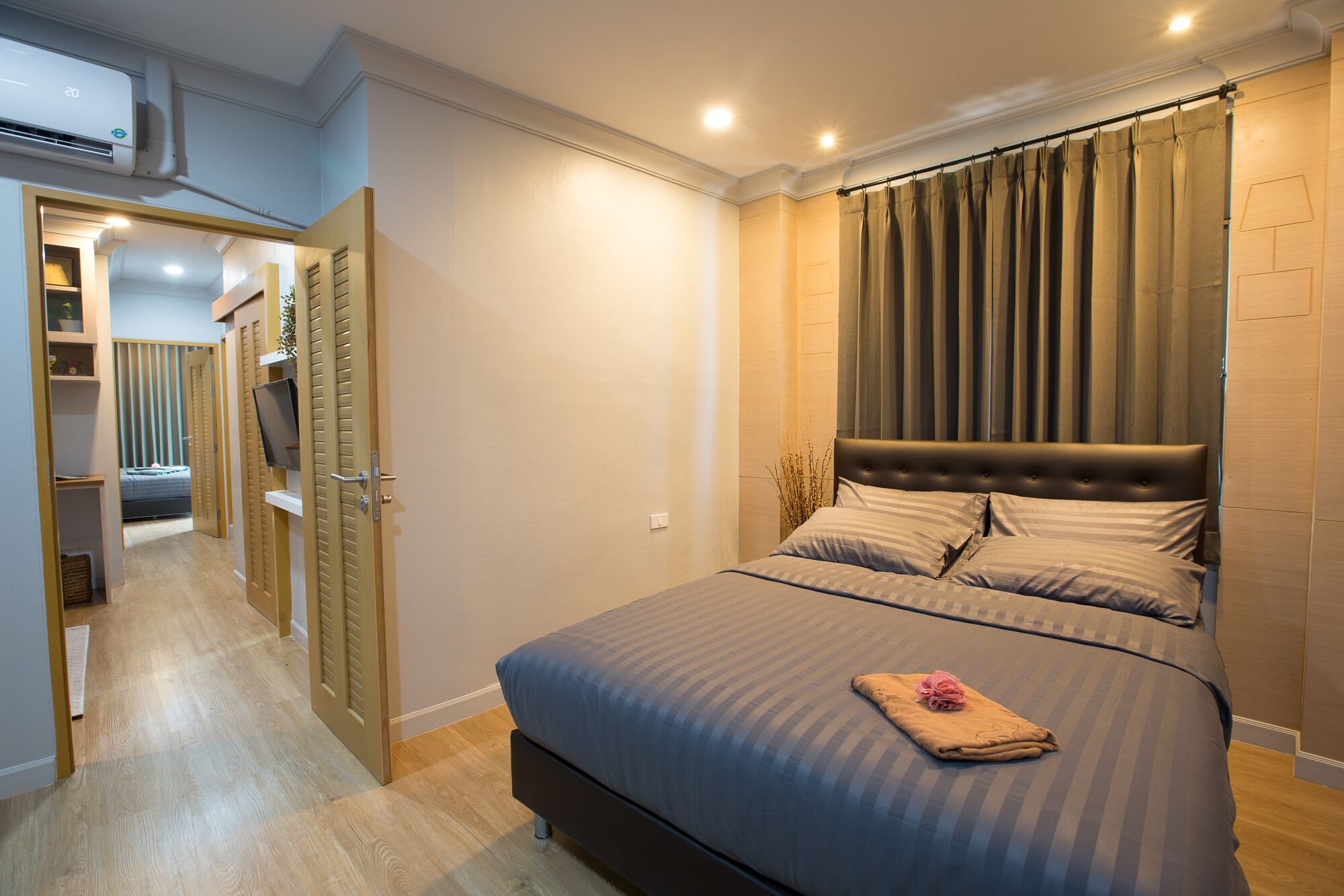 Un dormitorio moderno con una cama grande, un cabecero y una cortina.