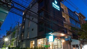 A modern hotel with a prominent sign, multiple floors, and a well-lit entrance. - PAMA House Boutique Hostel (Bangkok)