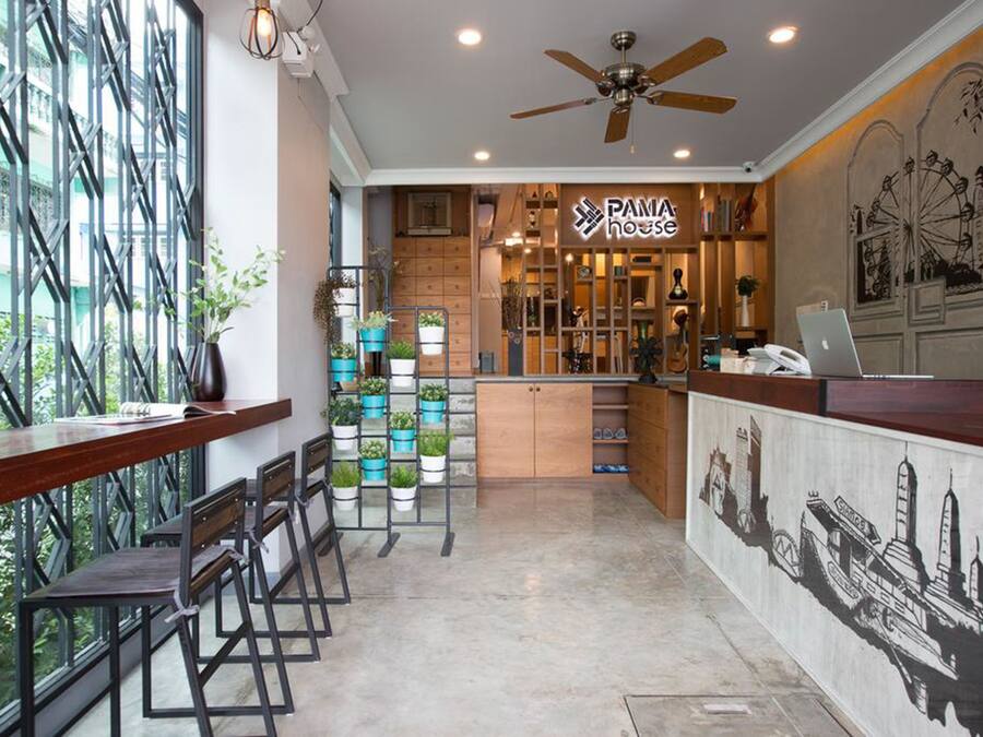 Um café moderno com balcão de madeira, banquetas e diversas plantas.