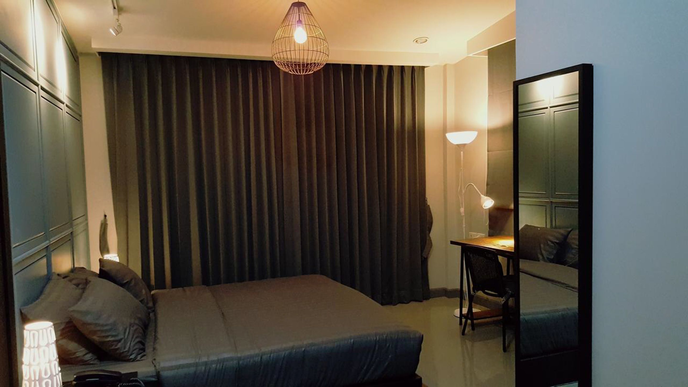 Ein Hotelzimmer mit Bett, Schreibtisch, Stuhl, Lampe und einem großen Spiegel.